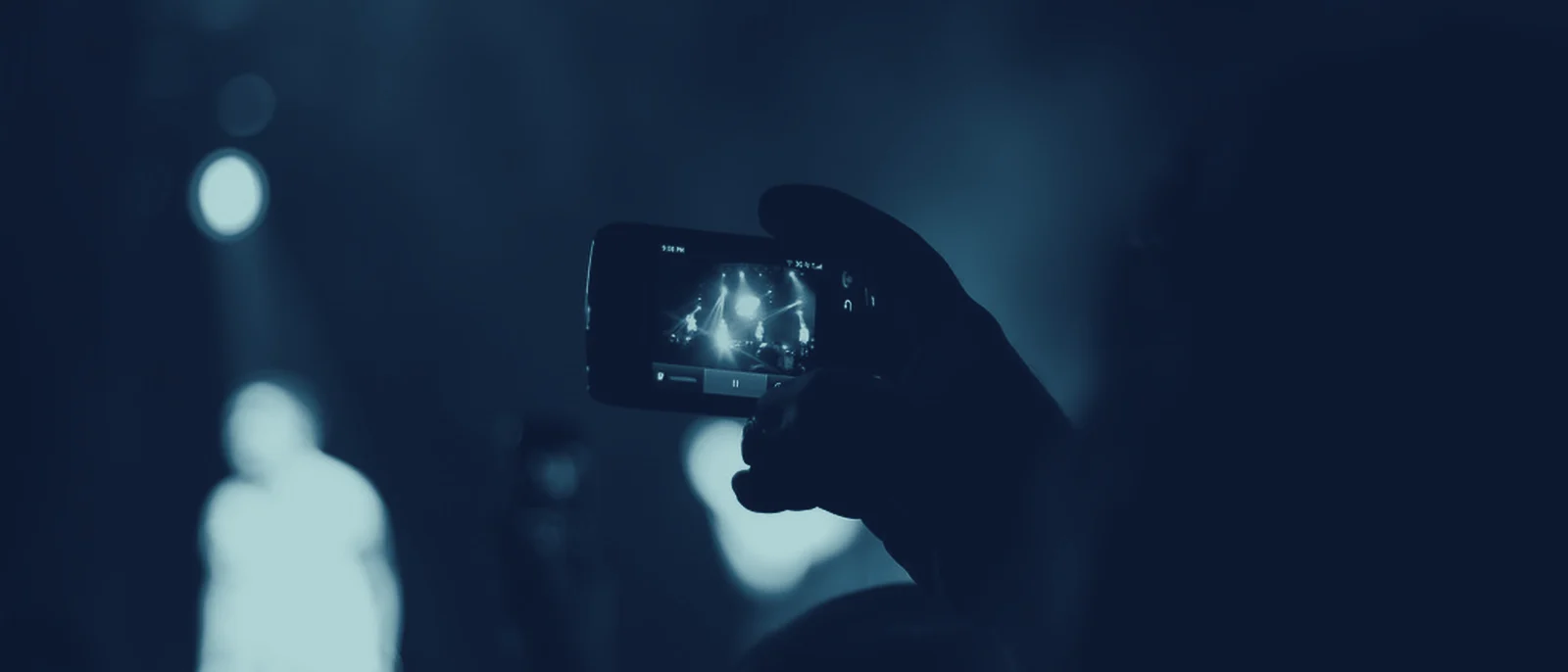 Une main filme la scène au smartphone, dans la foule